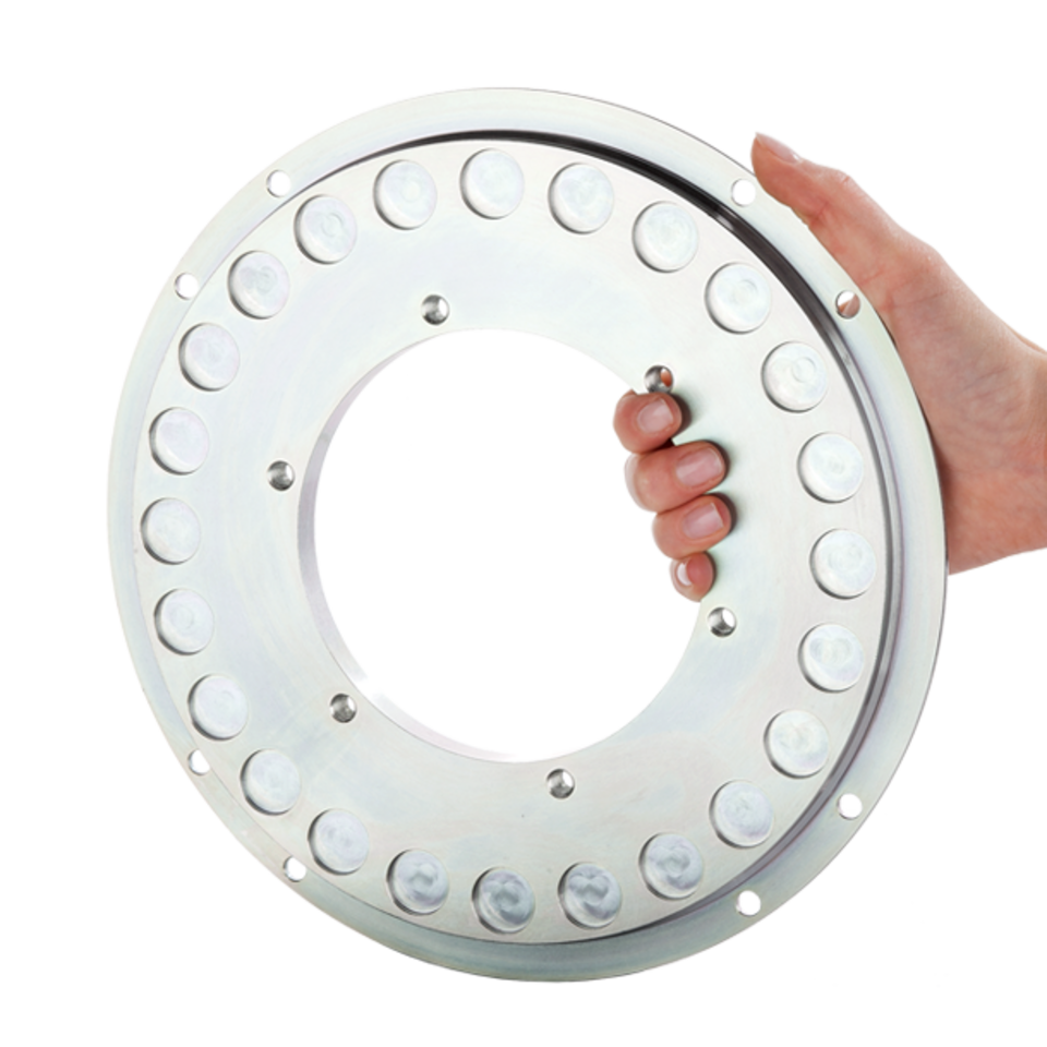 Eine Hand hält ein kreisrundes Bauteil aus Metall