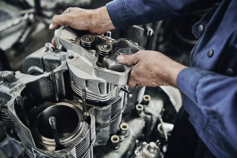 Ein Mitarbeiter von Schmid Metallbearbeitung arbeitet an einem Zylinderkopf