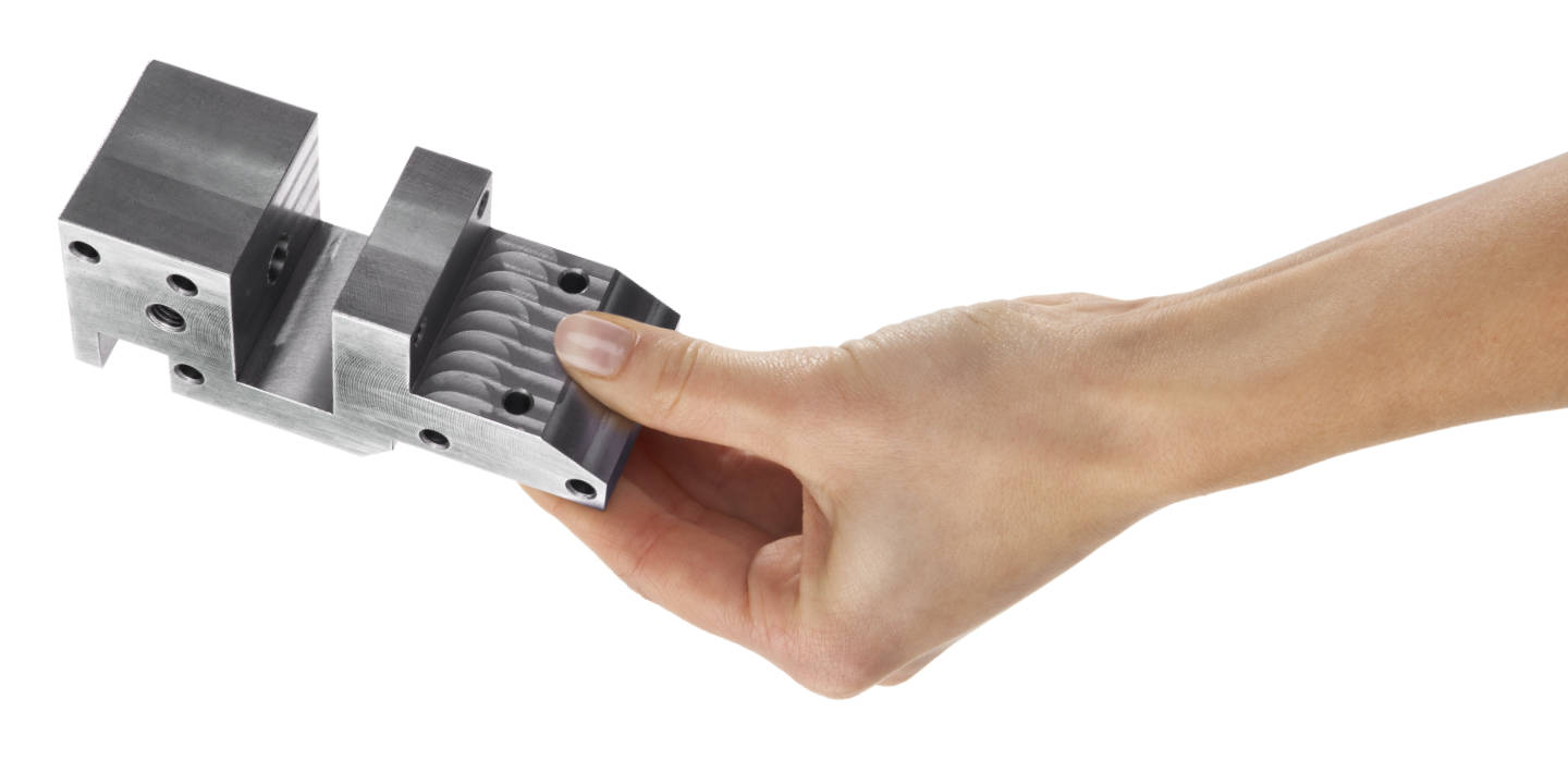 CNC-Frästeile Schmid Metallbearbeitung Eine Hand hält ein CNC-Frästeil aus Metall